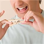 Close-up of a young man pinching his finger with a clothespin