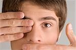 Close-up of a young man covering his mouth and his eye with his hands