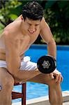 Close-up of a young man exercising with dumbbell