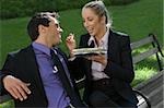 Homme d'affaires avec une femme d'affaires ayant des aliments sur un banc de parc