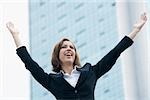 Close-up of a businesswoman smiling with her arms raised