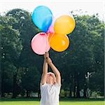 Boy holding balloons in a park