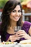 Portrait d'une jeune femme tenant un verre d'eau et souriant