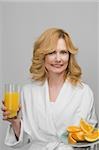 Portrait of a mature woman holding a plate of oranges and a glass of orange juice