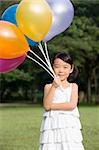 Portrait of a girl holding balloons in a park