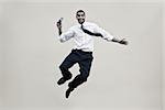 Portrait of a businessman holding a mobile phone and jumping