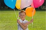 Portrait of a boy holding balloons in a park