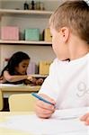 Close-up of a boy looking at a girl sitting behind him