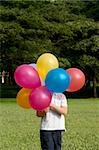 Boy holding balloons in a park