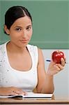 Porträt einer Lehrerin hält einen Apfel und grinst