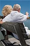 Rückansicht des ein altes Paar, sitzen auf einer Bank am See