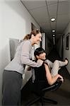 Two businesswomen playing in an office corridor