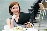 Portrait of a businesswoman holding a ring binder at a sidewalk cafe
