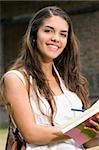 Portrait of a young woman writing in a notepad and smiling