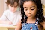 Close-up of a girl looking down with a boy sitting behind her