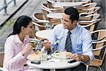 Businessman and a businesswoman having lunch at a sidewalk cafe