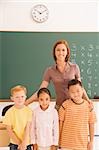 Portrait of a female teacher standing with her students in a classroom