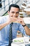 Portrait of a businessman eating a cheese sandwich