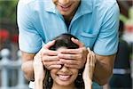Mid adult man covering eyes of a young woman with his hands
