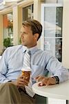 Businessman sitting in a restaurant and holding a disposable cup