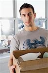 Portrait of a young man holding a cardboard box