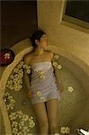 Young woman taking bath with flower petals