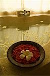 Bowl of flower petals on edge of bath