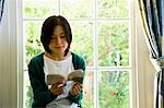 Young woman reading a book in front of window