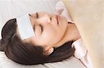 A woman sleeping with cooling sheet on her forehead