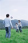 Family playing soccer in meadow