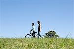 Young couple walking, woman pushing bicycle