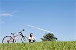 Young man sitting next to bicycle