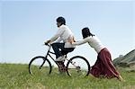 Young woman pushing young man on bicycle
