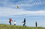 Four young people playing with beach ball