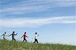 Four young people skipping in field