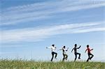 Four young people skipping in field