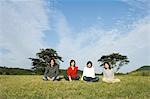 Four young people sitting in field