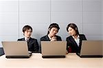Trois jeunes gens d'affaires à l'aide d'ordinateurs