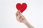 Woman's hand holding heart-shaped paper