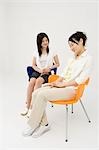 Zwei junge Frauen sitzen auf Stühlen