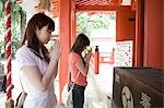 Two young women praying at shinto shrine