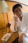Mature man using telephone in hotel room