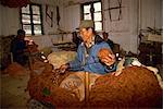 Portrait of a Tibetan man spinning wool in a carpet factory at a self-help centre in Darjeeling, India, Asia