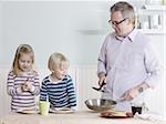 father and children making breakfast