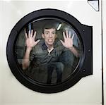 Mann im Inneren ein kommerzieller Wäschetrockner in einem Waschsalon