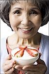 senior woman with a bowl of cereal and strawberries