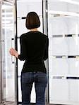woman looking into empty refrigerators at market