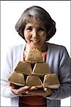 senior woman holding a stack of gold bricks