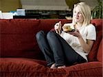 woman eating a muffin on a red sofa