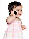 baby girl in a pink dress holding a cell phone